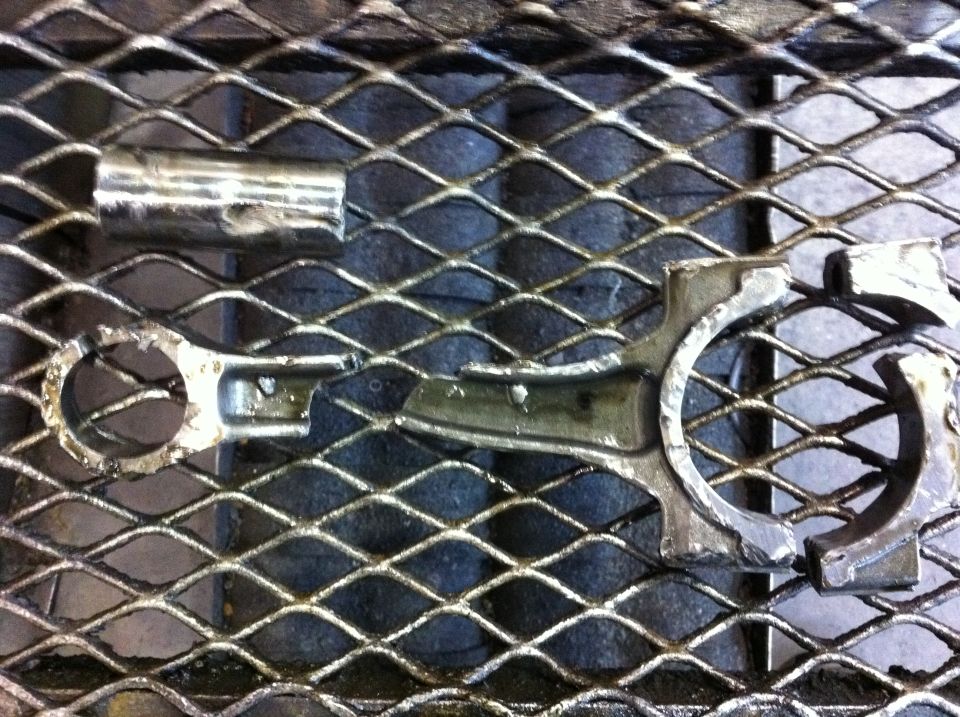 Broken engine connecting rod and cap on a metal grate