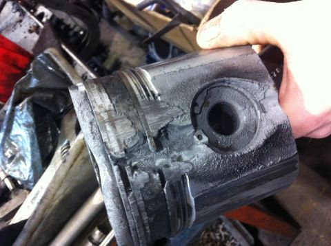 1990 Ford Bronco - A heavily damaged engine piston, likely from catastrophic engine failure, is held for inspection.