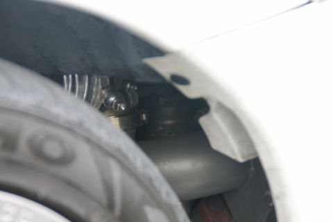 1993 Ford Taurus - A close-up view of a hose clamp and tubing, likely part of the suspension or engine bay, visible within a vehicle's wheel well.