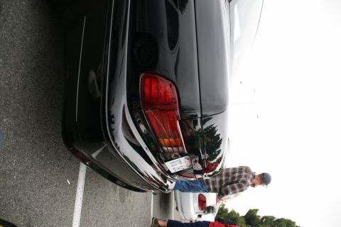 1993 Ford Taurus - A close-up view of the rear of a black sedan, parked next to a white vehicle.