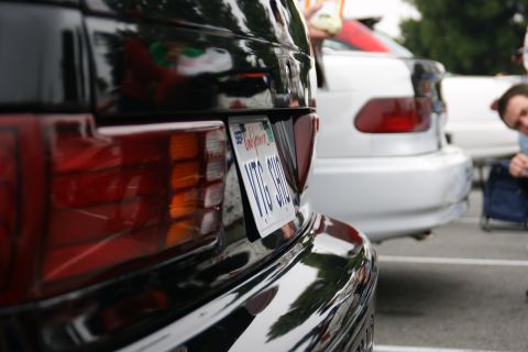 1993 Ford Taurus - A black car's rear is visible, parked behind a white car, with a person in the background.