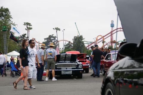 1993 Ford Taurus - An outdoor gathering of car enthusiasts with amusement park rides visible in the distance.