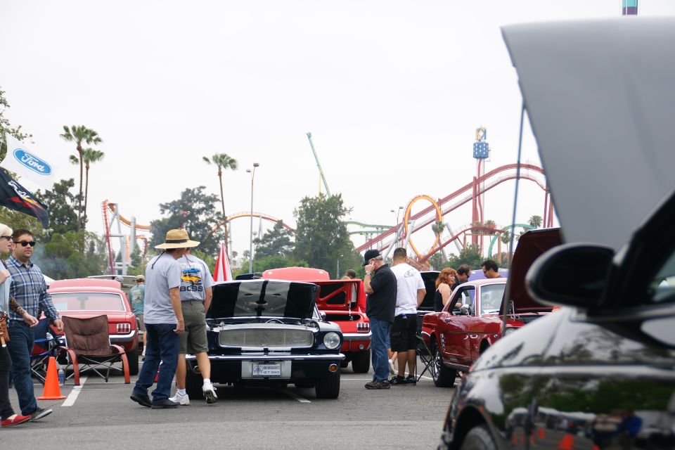 Black 1967 Ford Mustang with racing stripes, hood open, parked at an outdoor event