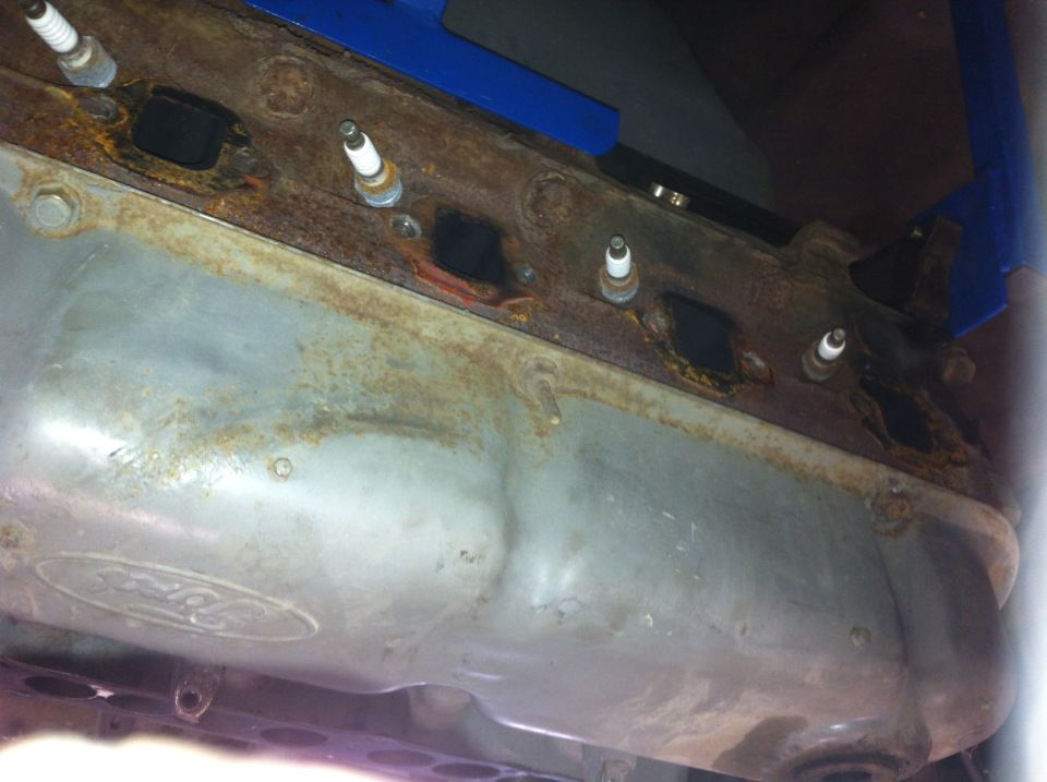 close-up of rusty engine part with spark plugs, Ford logo visible on metal pan