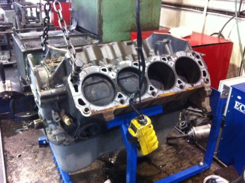 1990 Ford Bronco - Engine block being worked on in a garage setting, with chains and a yellow device attached.