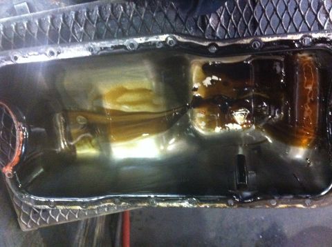 1990 Ford Bronco - The oil pan shows signs of old, dark oil and some lighter colored sludge accumulation.