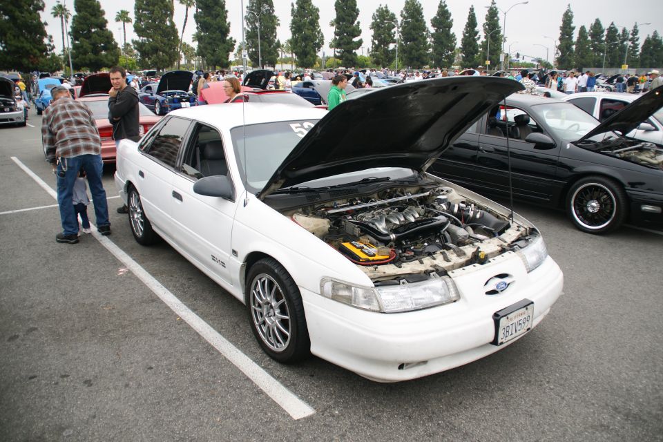 White sedan with hood open, showing engine. Silver rims, dark tinted windows. License plate visible