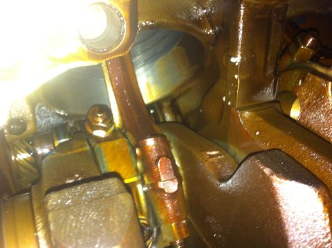 1990 Ford Bronco - Engine internals, likely oil pan and connecting rod, covered in oil.