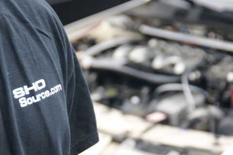 1993 Ford Taurus - A person stands in front of an open engine bay, wearing a t-shirt with a website logo.