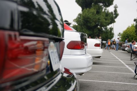 1993 Ford Taurus - Several cars are parked in a lot, with a focus on the rear of a black vehicle in the foreground.