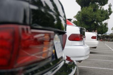 1993 Ford Taurus - A line of white cars are parked in a lot, viewed from the rear.