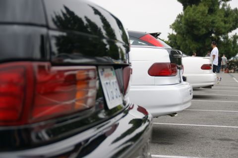 1993 Ford Taurus - Three cars are parked in a lot, showing their rear ends and taillights.