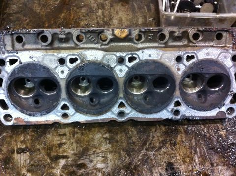 1990 Ford Bronco - Engine cylinder head showing four combustion chambers and visible casting marks.