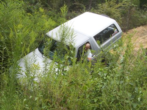 1995 Ford Bronco - A driver navigates a white SUV through dense vegetation on a wooded trail.