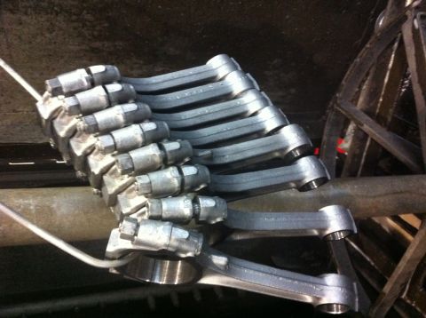 1990 Ford Bronco - Multiple silver suspension control arms are arranged in a stack, ready for installation.