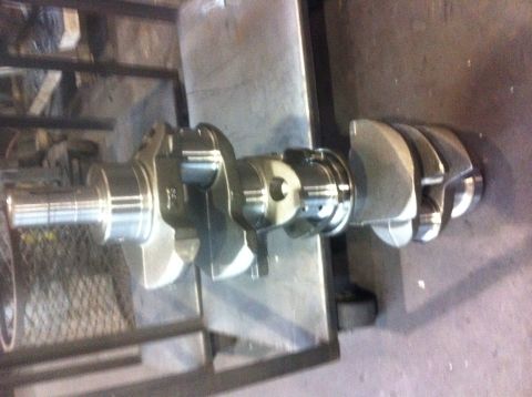 1990 Ford Bronco - A polished crankshaft is displayed on a workbench, with the Supermotors.net logo in the lower right corner.