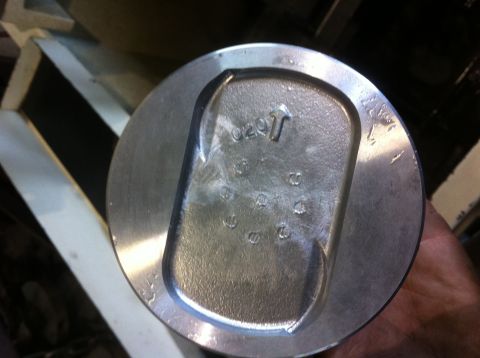 1990 Ford Bronco - This is a close-up view of an engine piston, showing some cast-in markings and numbers.