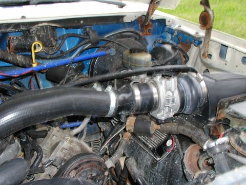 1990 Ford Bronco - Engine bay of a 1990 Ford Bronco, showing various hoses, wiring, and engine components under the hood.
