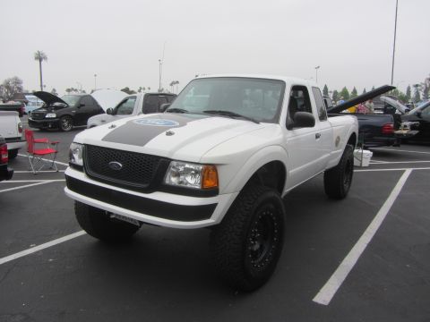 1964 Ford Ranchero - A lifted Ford Ranger pickup truck is parked in a lot with other vehicles under an overcast sky.