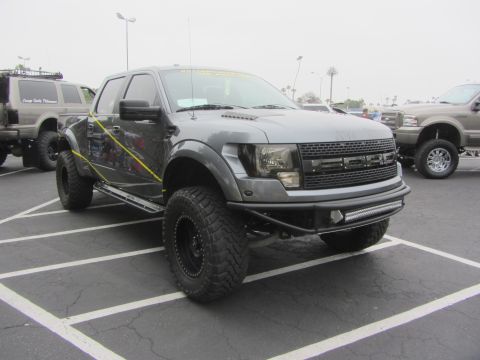 1964 Ford Ranchero - A modified gray Ford F-150 Raptor is parked in a lot with other vehicles.