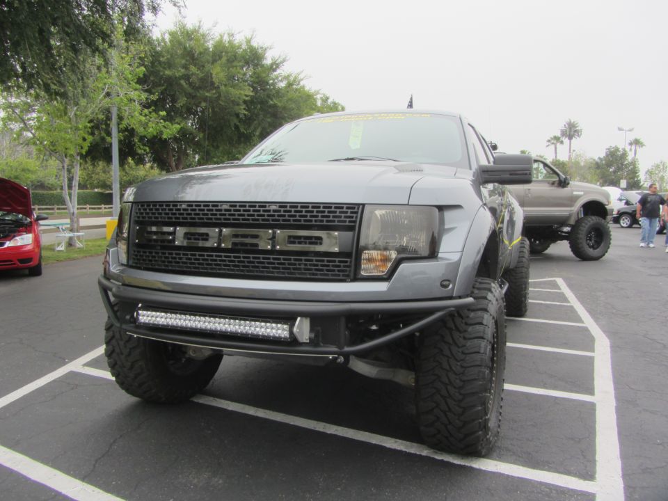 Gray Ford F-150 Raptor front view with aftermarket bumper and light bar