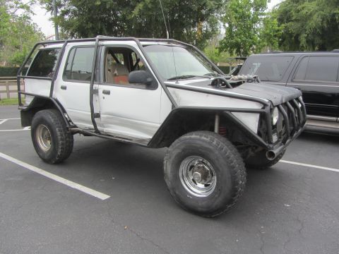 1964 Ford Ranchero - Modified SUV with extensive roll cage and off-road modifications, parked next to another vehicle.
