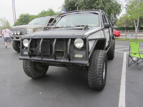 1964 Ford Ranchero - A heavily modified SUV with a custom front bumper and roll cage is parked in a lot.