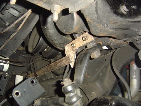 1986 Ford Bronco - Close-up of a rusty steering box bracket and linkage assembly, showing mechanical components.