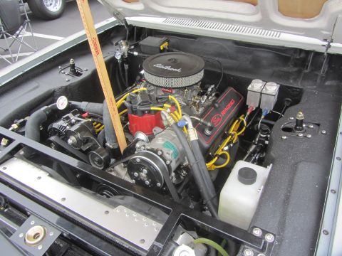 1964 Ford Ranchero - The engine bay of a vehicle, a V8 engine with an Edelbrock air cleaner and prominent yellow spark plug wires.