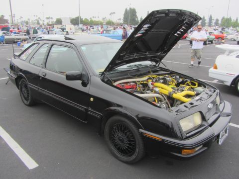 1964 Ford Ranchero - A black Ford Sierra XR4Ti is displayed with its hood open, revealing the engine bay, at an outdoor car event.