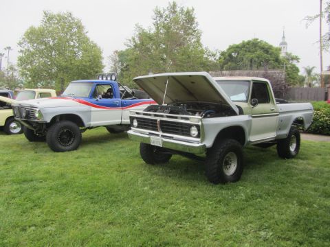 1964 Ford Ranchero - Two custom pickup trucks are displayed on a grassy lawn, one with its engine exposed.