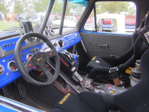 1964 Ford Ranchero - The interior of a heavily modified vehicle features racing seats, a roll cage, and a vibrant blue dashboard with multiple gauges.