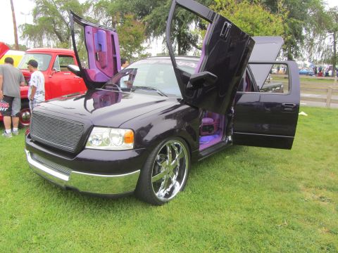 1964 Ford Ranchero - This customized Ford F-150 features unique upward-opening doors and a vibrant purple interior.