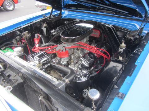 1964 Ford Ranchero - The engine bay of a 1964 Ford Ranchero features a V8 engine with chrome accents and bright red spark plug wires.