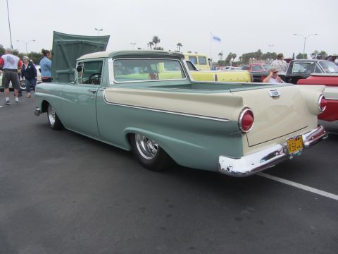 1964 Ford Ranchero - A classic two-tone Ford Ranchero is parked at a car show with its hood up.