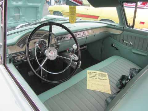 1964 Ford Ranchero - The interior of a light blue 1956 Ford Fairlane features a two-tone dashboard and a yellow flyer on the seat.