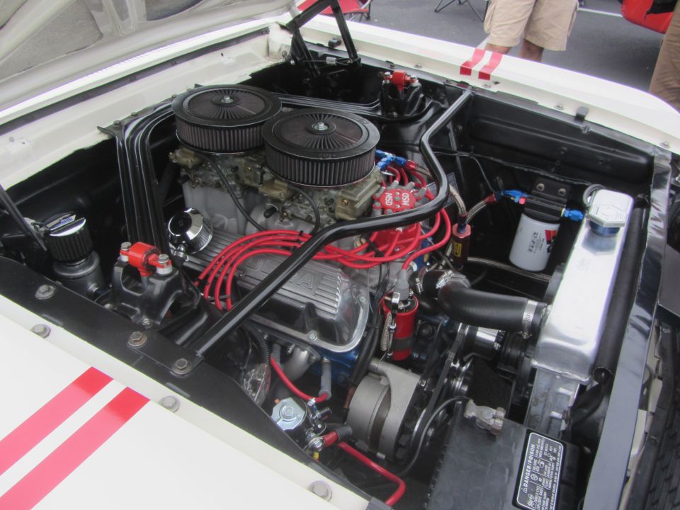 White 1964 Ford Ranchero engine bay with dual carburetors, red spark plug wires, and aluminum radiator