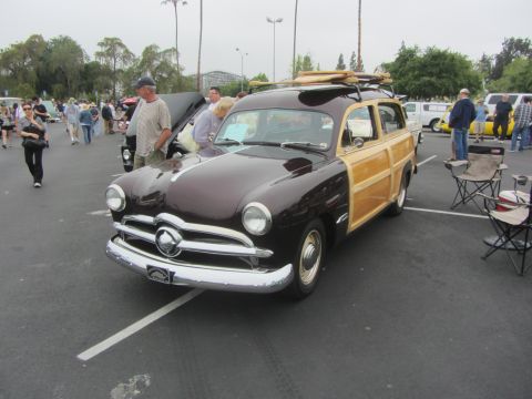1964 Ford Ranchero - A classic 1950 Ford Woody Wagon is displayed at an outdoor event, complete with surfboards on its roof rack.