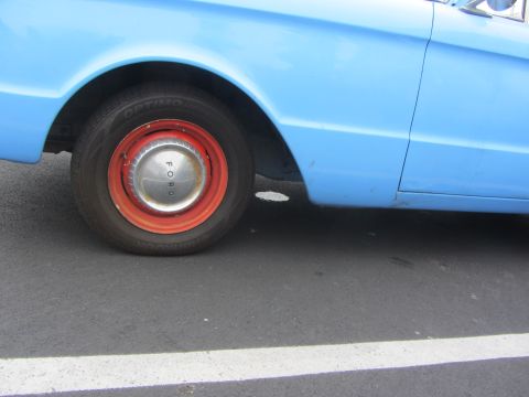 1964 Ford Ranchero - A blue 1964 Ford Ranchero is seen from the side, focusing on its wheel and fender.