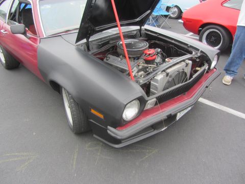 1964 Ford Ranchero - A red and black pickup truck is shown from the front with its hood open, revealing the engine compartment.