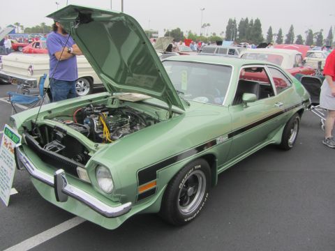 1964 Ford Ranchero - This green coupe, likely from the 1970s, is displayed with its hood open, revealing the engine compartment.