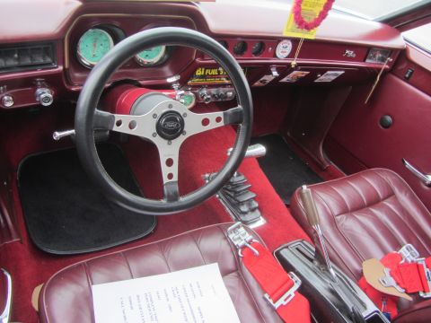 1964 Ford Ranchero - The interior of a 1964 Ford Ranchero shows a red dashboard, floor mats, and seats with racing harnesses.