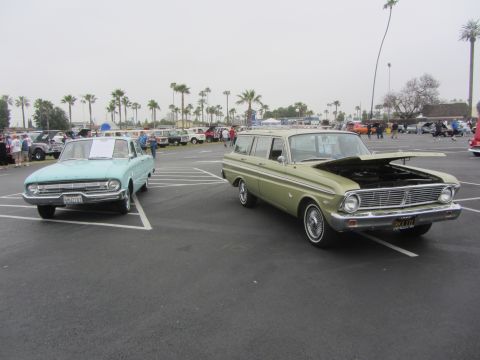 1964 Ford Ranchero - A light green 1964 Ford Falcon Squire wagon and a light blue 1964 Ford Falcon sedan are displayed at an outdoor car show.