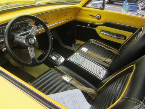 1964 Ford Ranchero - The interior of a 1964 Ford Ranchero features a yellow dashboard and black seats with yellow piping.