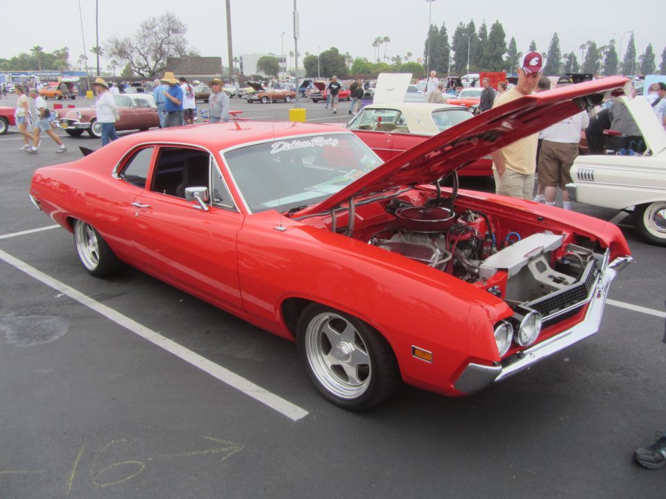 Red 1970 Ford Torino GT with hood open, parked at car show