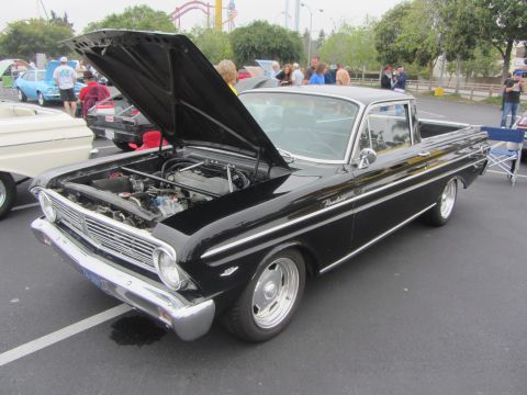1964 Ford Ranchero - A black pickup truck is parked with its hood open, revealing the engine bay.