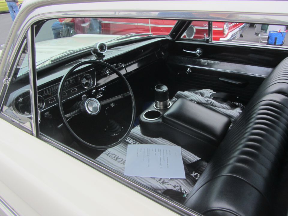 1964 Ford Ranchero interior with black seats, dashboard, steering wheel, and a document on the passenger seat