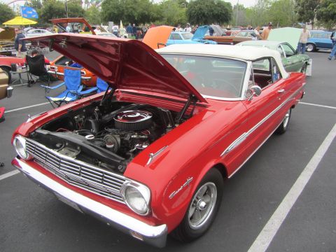 1964 Ford Ranchero - A red 1963 Ford Falcon convertible is displayed with its hood up at an outdoor event, revealing the engine bay.