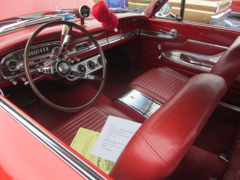 1964 Ford Ranchero - The interior of a classic red Ford Falcon shows its vintage dashboard, steering wheel, and seating.
