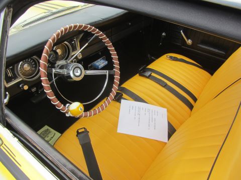 1964 Ford Ranchero - The interior of a 1964 Ford Ranchero features bright yellow seats with black stripes and a unique steering wheel adorned with a billiard ba…